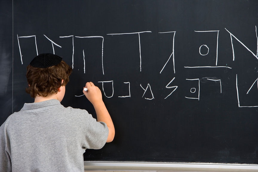 Boy Writing Hebrew Letters on Blackboard