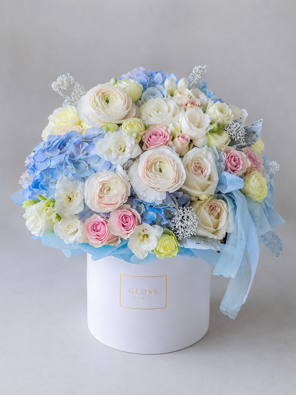 Pink and blue garden flower arrangement in a hatbox