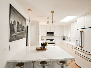 Modern San Diego kitchen remodel with white shaker cabinets, quartz island with seating, gold hardware, pendant lighting, and skylight for natural light.