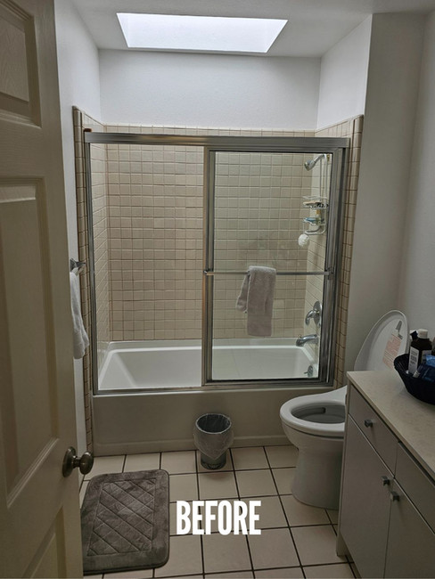 Before photo of a La Jolla bathroom with an alcove tub-shower combo, older tile walls, and a skylight before the remodel.