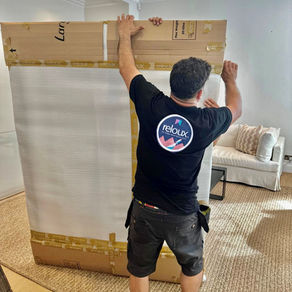 A member of the Reloux moving team meticulously secures a large, wrapped package in an elegantly decorated living space, ensuring a safe transit.