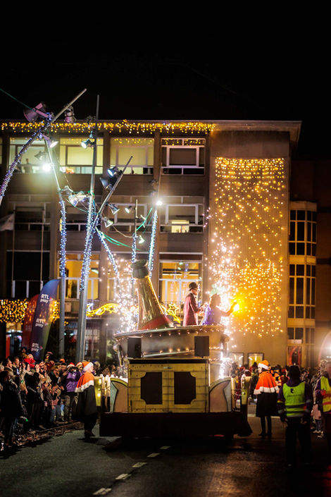 Verlichte carnavalswagen met vuurwerk in de avond.