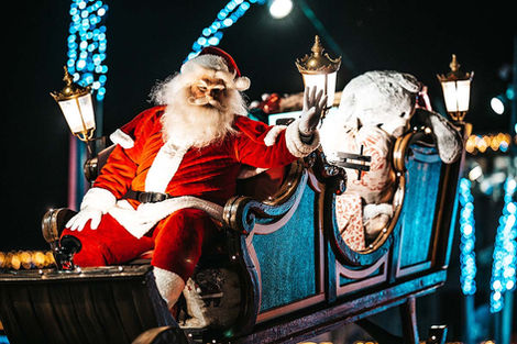 De Kerstman zwaaiend vanuit zijn arrenslee in het donker.