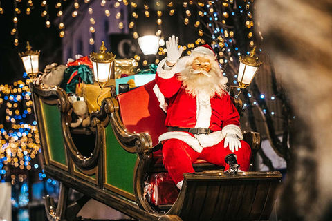 De Kerstman zwaait vanuit zijn arrenslee vol cadeaus.