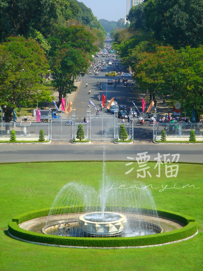 前景綠色草地上有一座噴泉，遠景是越南的法式大道