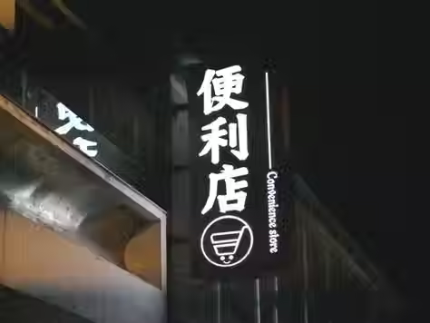 Convenience store sign at night with japanese text.