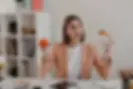Food consultant in Singapore wearing pink jacket choosing between burger and apple while seated at workplace desk