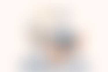 Person asleep at a desk, head on laptop. Books, mug, and cactus nearby. Clock shows time, light overhead. Scene is calm, colors are muted.