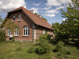 Seitenansicht von einem Backsteinhaus mit Garten und Baumen und Pflanzen.