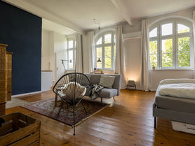 großer Raum mit Bett, Sofa, Sessel und Essbereich und großem Eck-Kamin.