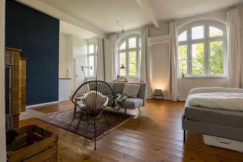 großer Raum mit Bett, Sofa, Sessel und Essbereich und großem Eck-Kamin.