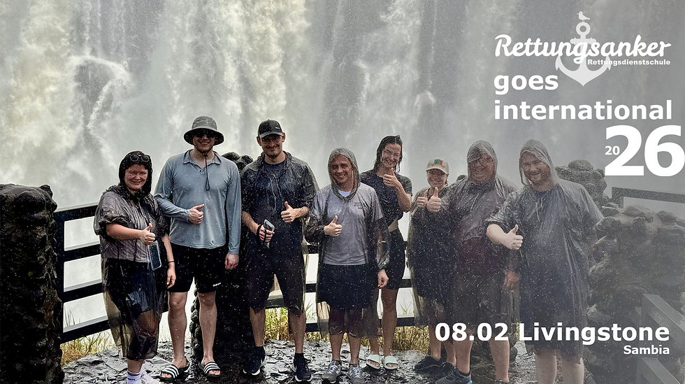 Gruppe der Rettungsanker Rettungsdienstschule ® am Aussichtspunkt der Victoriafälle – Gischt, Regen und Teamfoto in Livingstone.