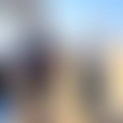 Dozenten und Teilnehmende machen eine kurze Pause am Geländewagen in den Dünen; im Hintergrund Wüste und Meer bei Walvis Bay.