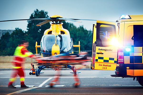 Rettungseinsatz mit Rettungshubschrauber und Rettungswagen der Rettungsdienstschule Rettungsanker® – Rettungssanitäter transportieren einen Patienten auf der Trage.