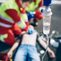 Rettungssanitäter leisten Reanimation an einem Patienten, im Vordergrund hängt eine Infusion – praxisnahes Training im Rettungsdienst.