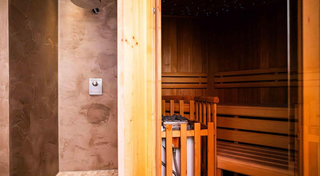 Holzsauna mit Bänken und moderner Duschbereich