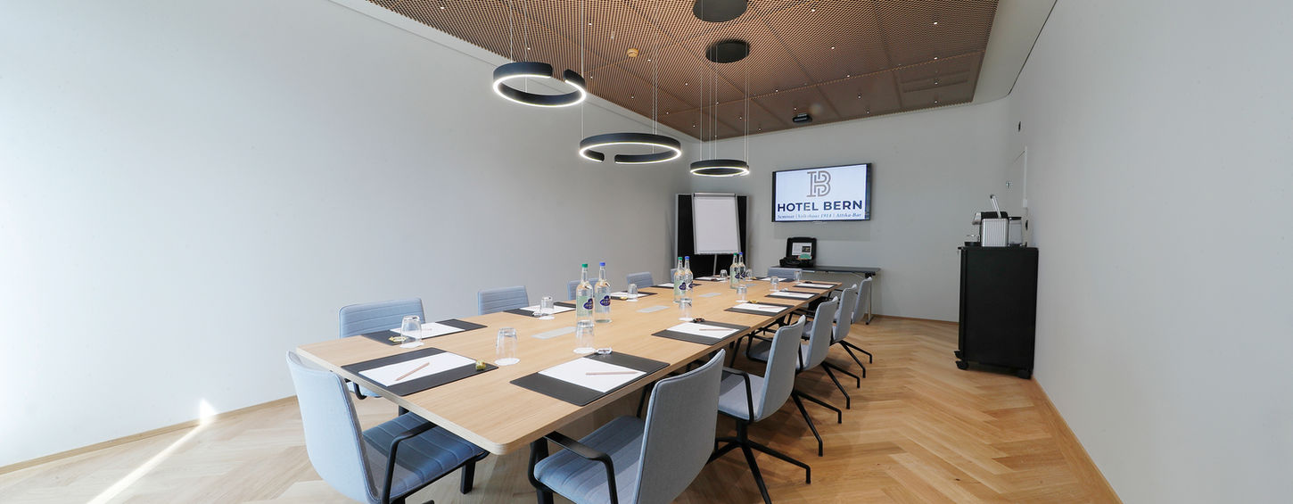 Moderner Konferenzraum mit Holztisch und Hotel Bern Logo