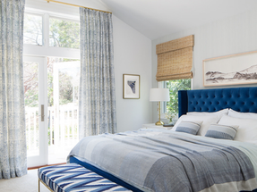 Primary bedroom with french doors, light walls and accents of blue.