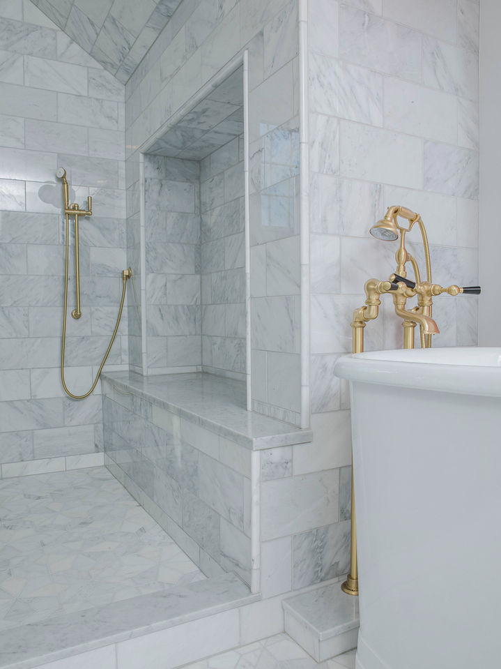 Modern residential marble shower with gold fixtures.