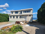 Nearly finished exterior of the two-story home at 145 Sauga Ave. with blue sky and the bay beyond