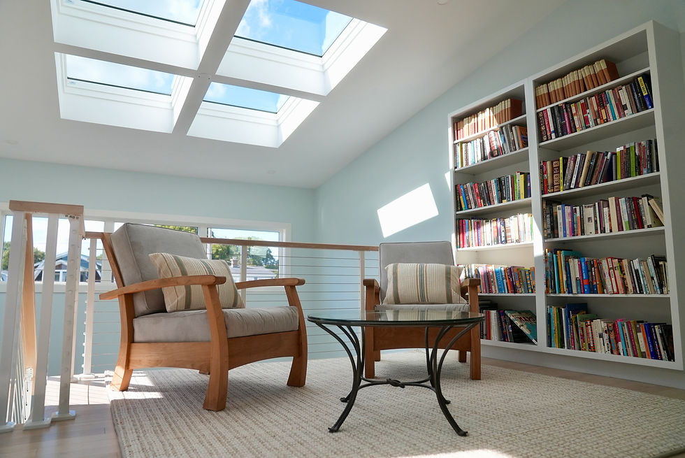 Sitting room with wooden armchairs, built-in bookshelves, and skylights
