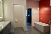 Bathroom with a red accent wall and a doorway to the next room in a custom home in North Kingstown