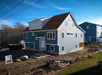 Rebuilt blue home with a brown roof at 141 Maple Ave., with the yard still being graded