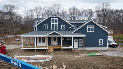 Front of the home with blue siding, white trim, and a covered front porch during construction