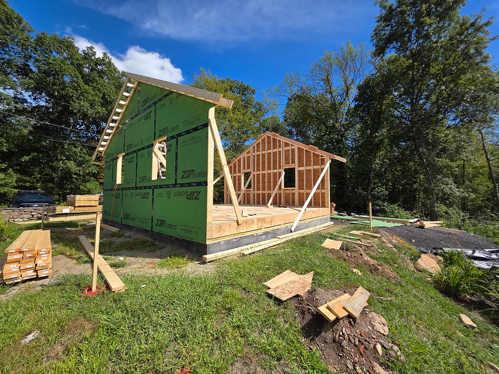 Wood-framed building under construction with sheathing and lumber stacked on the site in Rhode Island