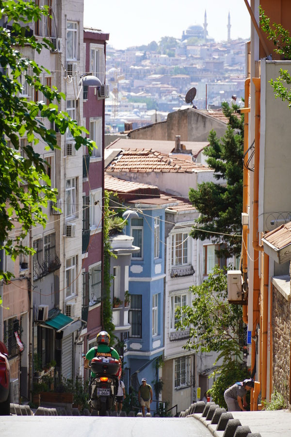 Wąska stroma ulica, jedzie motocykl