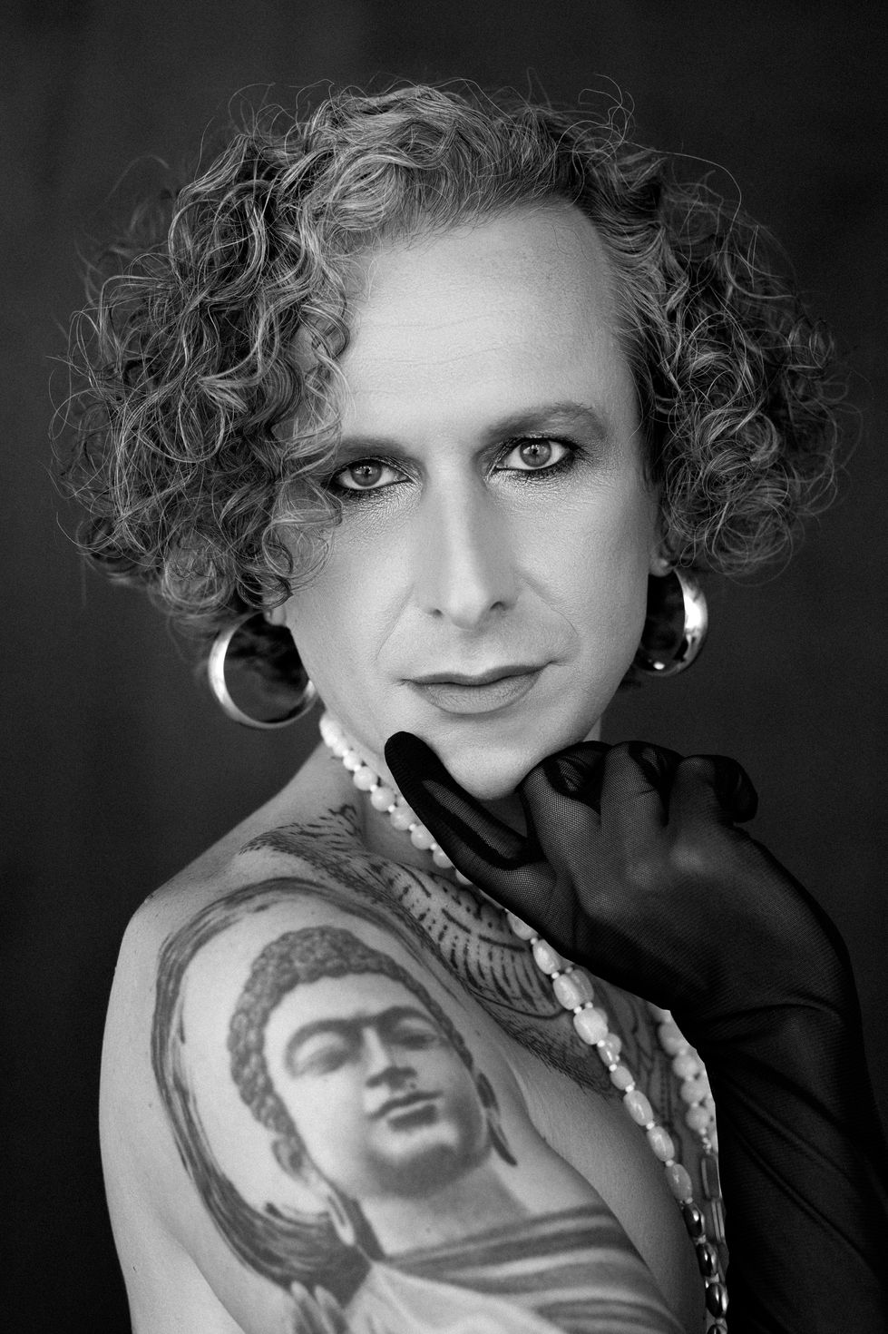 Close-up of elegant transgender model wearing earrings and black gloves – noir beauty