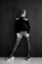 Tattooed trans fashion model Leia in black-and-white editorial photo, showcasing full sleeve ink and bold gaze.