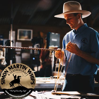 Simon Martin standing in his workshop braiding leather to make handcrafted whip.