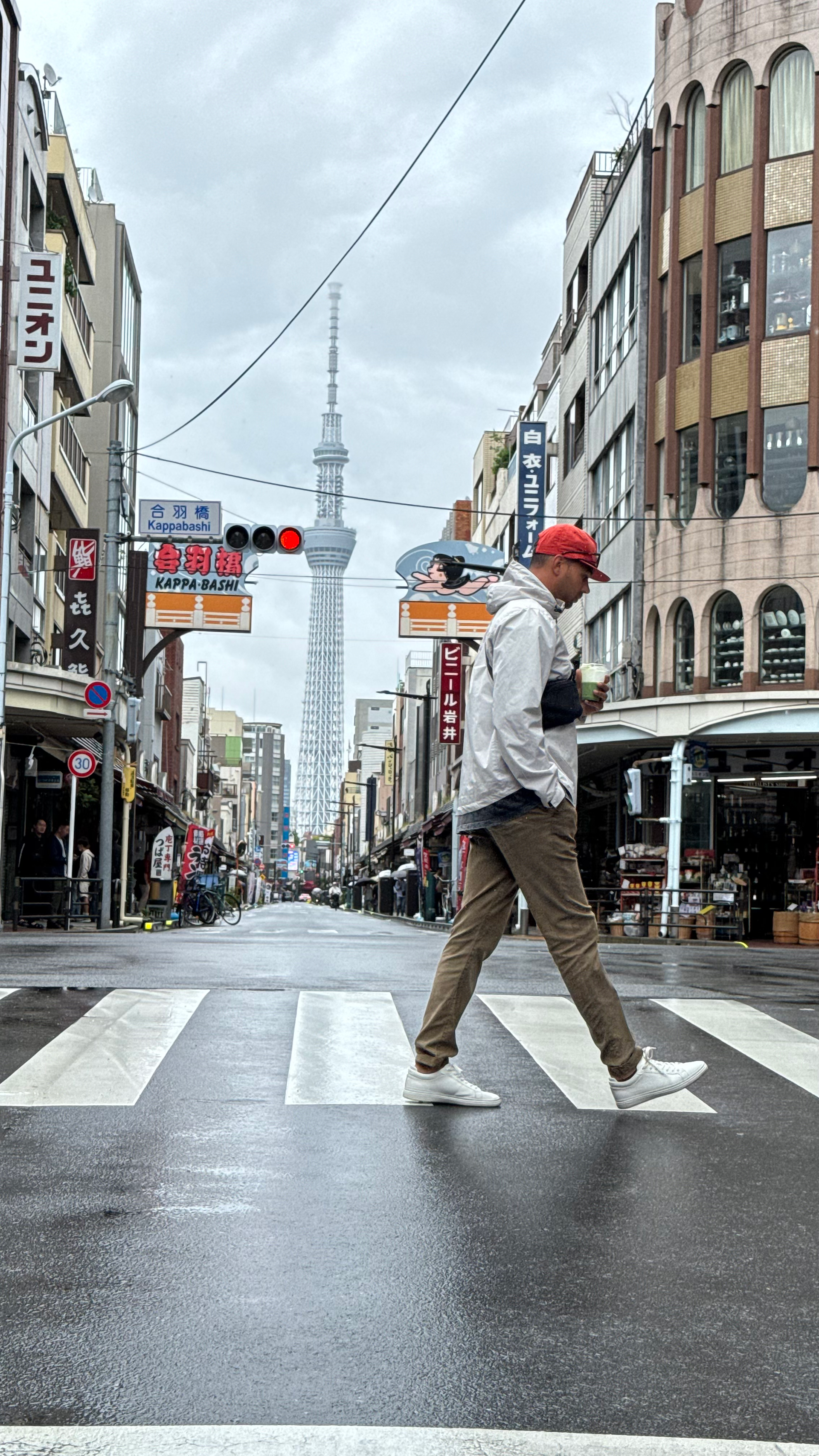 man crosses street in tokyo with matcha latte in hand