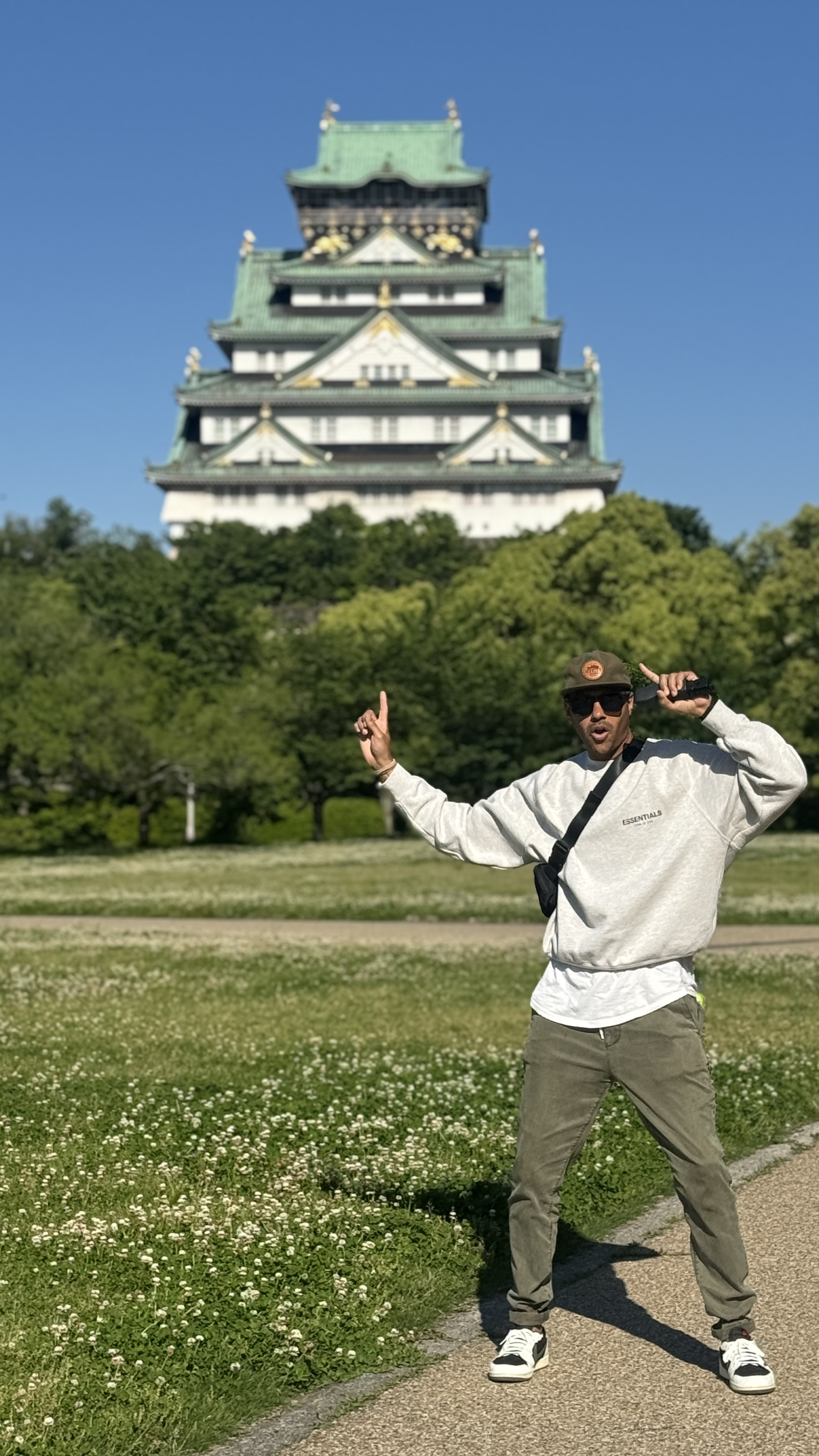 man points in photo at Osaka Castle in japan