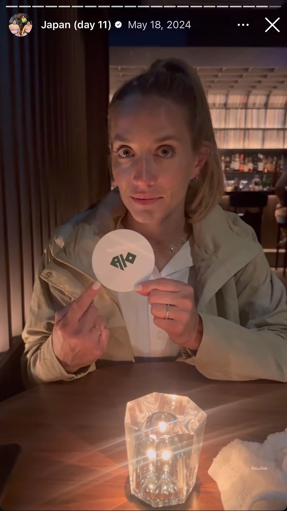 woman holds up and points to coaster in japanese bar