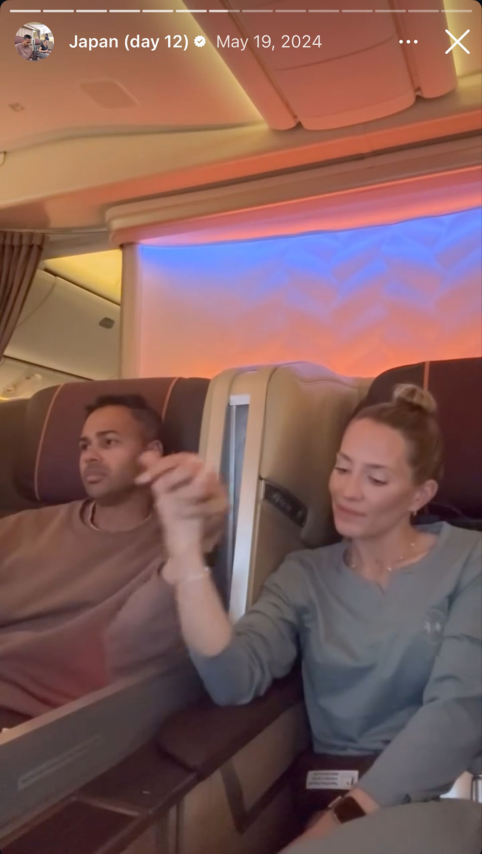 man and woman hold hands in business class airplane seats