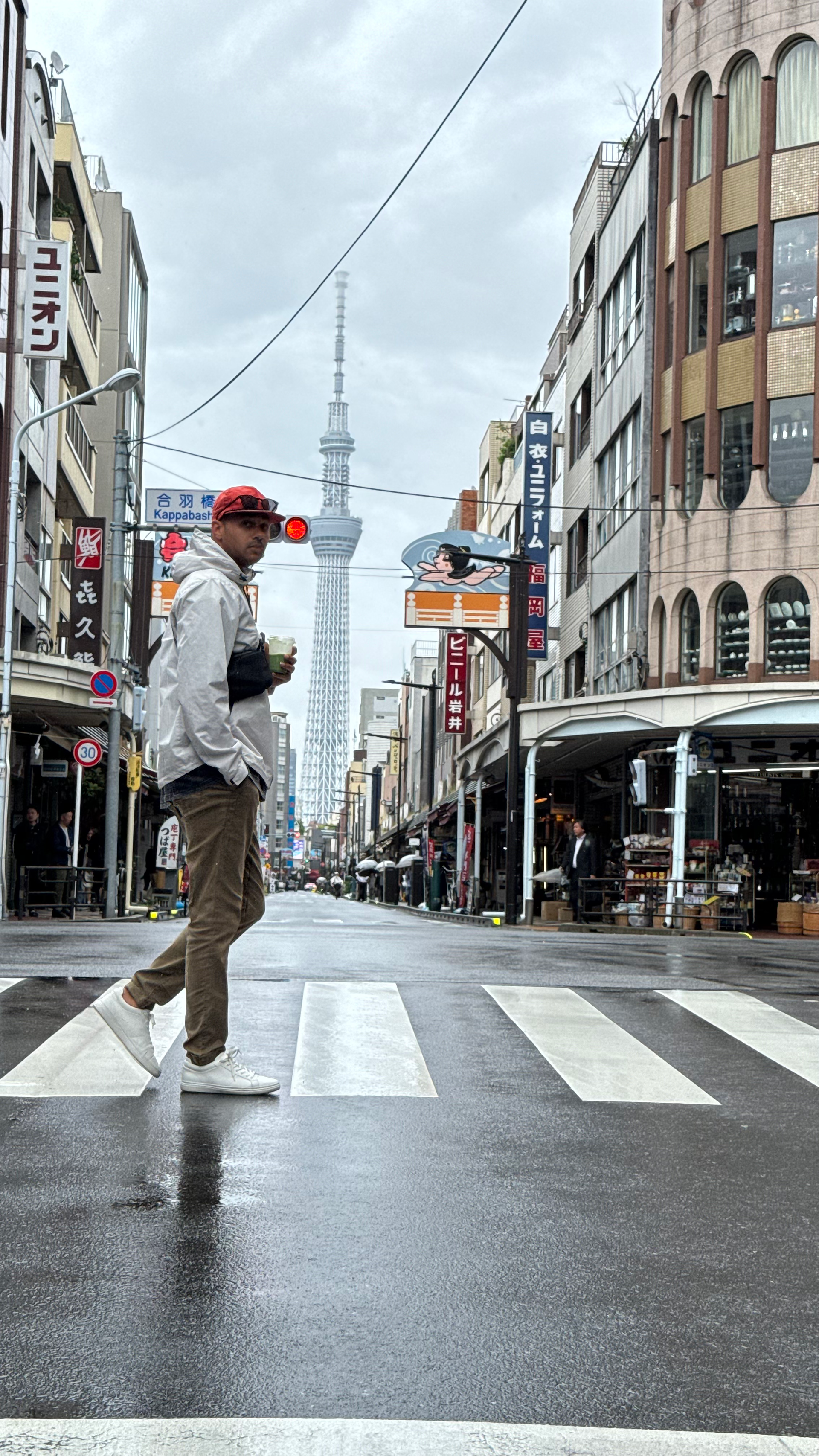 man crosses street in tokyo with matcha latte in hand