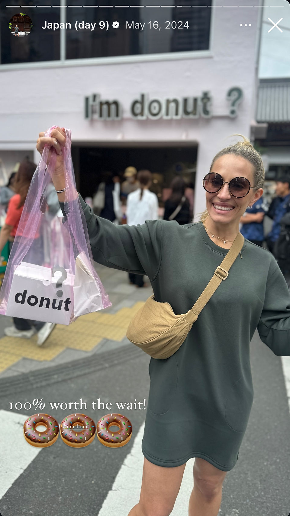 woman holds up bag of donuts in japanese crosswalk