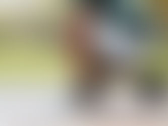 Person crouching in a park and holding the back of their ankle, illustrating Achilles tendon pain