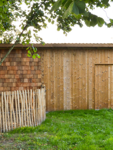 Natuurlijke tuin met tuinberging in thermowood en kastanje afsluiting