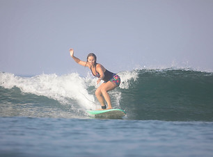 surfing a wave in goa while standing on a surfboard