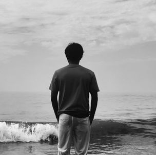 Rückenansicht einer Person am Meer, die ruhig auf den Horizont schaut – Symbol für Reflexion und innere Auseinandersetzung