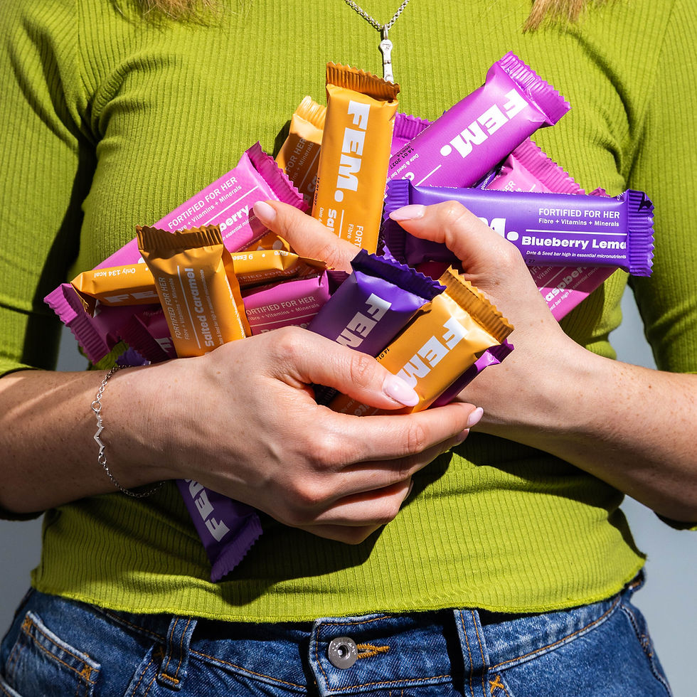 A women wearing a green top is holding lost of FEM health bars in her hands against her body. They look like they are going to fall out of her hands.