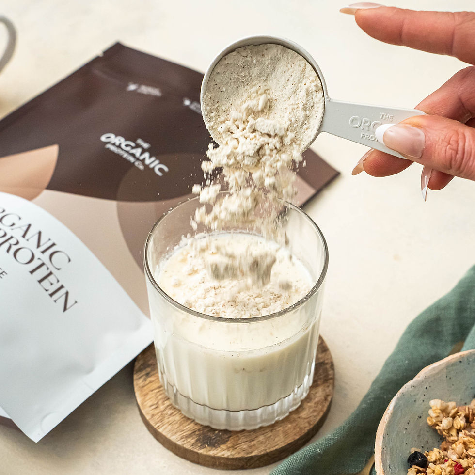 A hand tipping protein powder into a glass of milk with the protein bag in the background