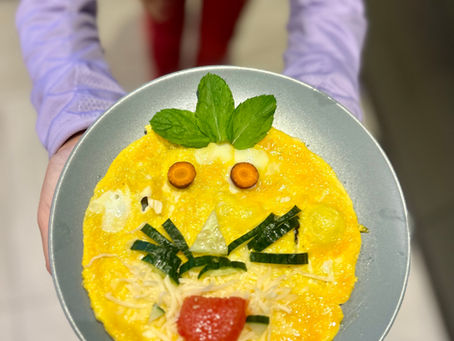 Enfant présentant une omelette décorée avec des légumes – alimentation équilibrée de l’enfant