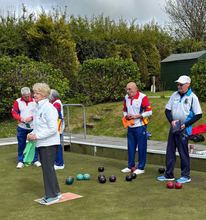 Group of adults playing lawn bowls on a green