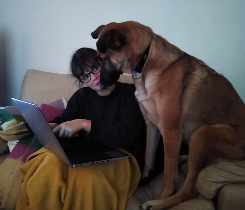 Photo of Rachel and her dog on the couch, she is showing him the latop.