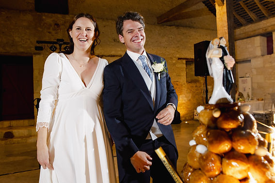 Portrait des mariés à côté de leur pièce montée lors de la soirée de mariage au Château de la Tour d'Oyré.