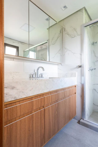 Banheiro reformado pela Agata com acabamentos em madeira e pedra branca